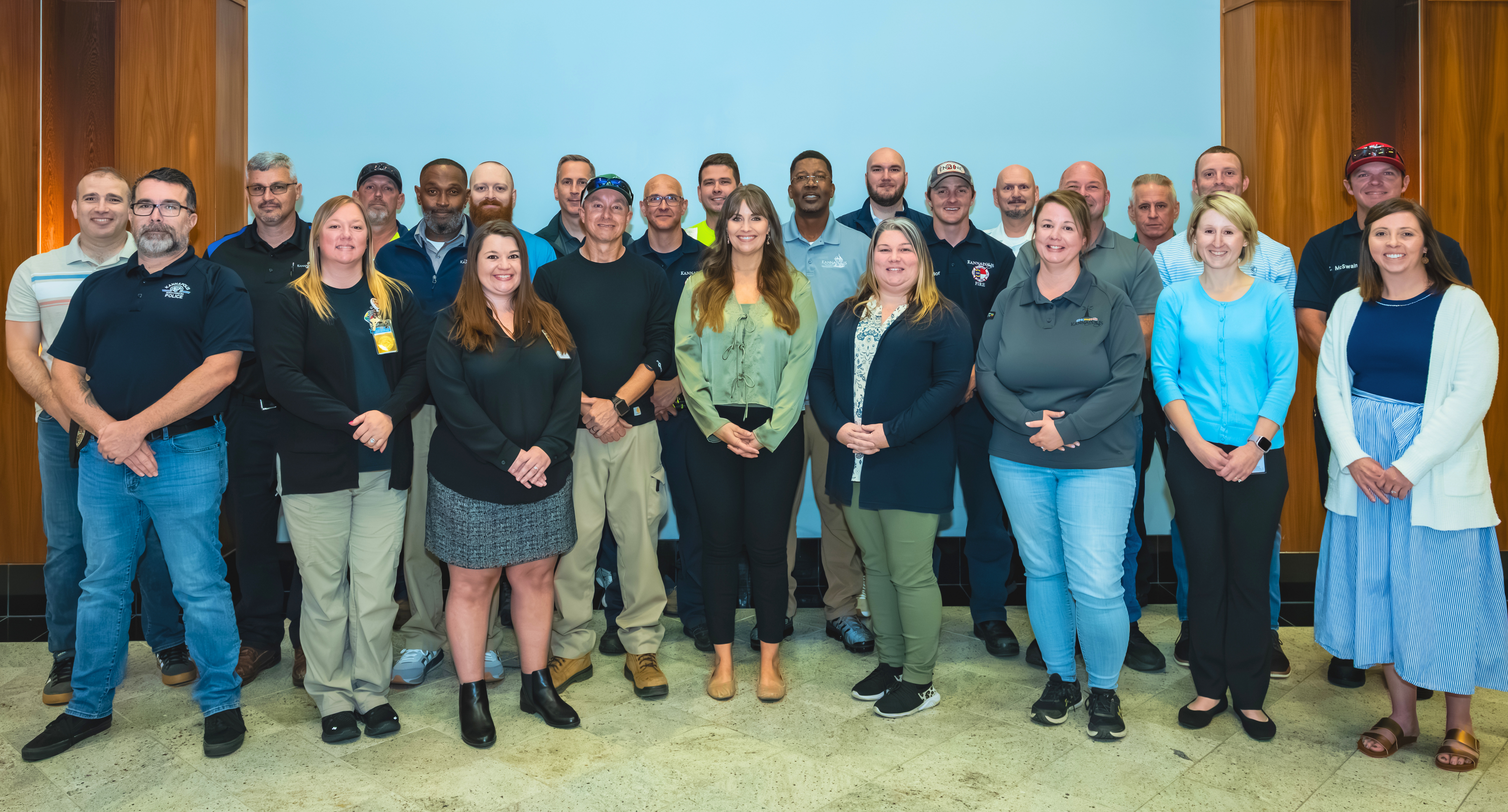 Group of 30 Kannapolis employees standing in 3 rows smiling for a photos Group of 30 Kannapolis employees standing in 3 rows smiling for a photos